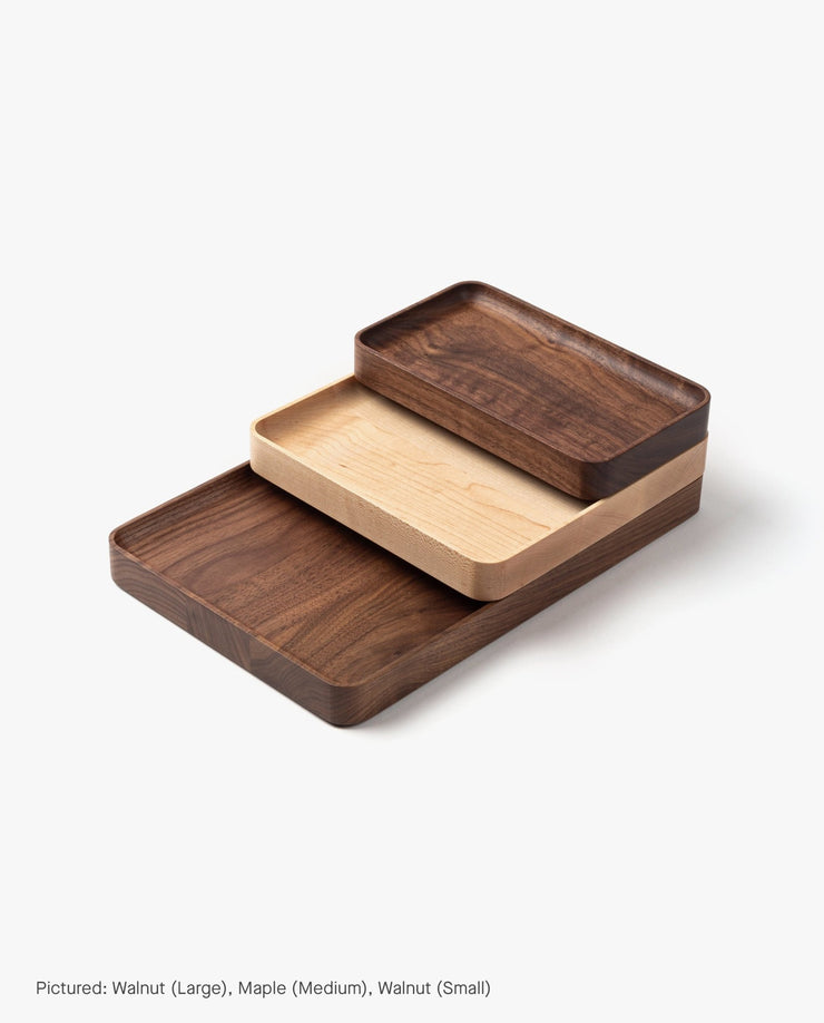 The medium valet tray, crafted from solid maple with rounded corners, nests between two walnut trays (largest and smallest) for a stylish set, shown on a white background. Product: Valet Tray (Maple - Medium).