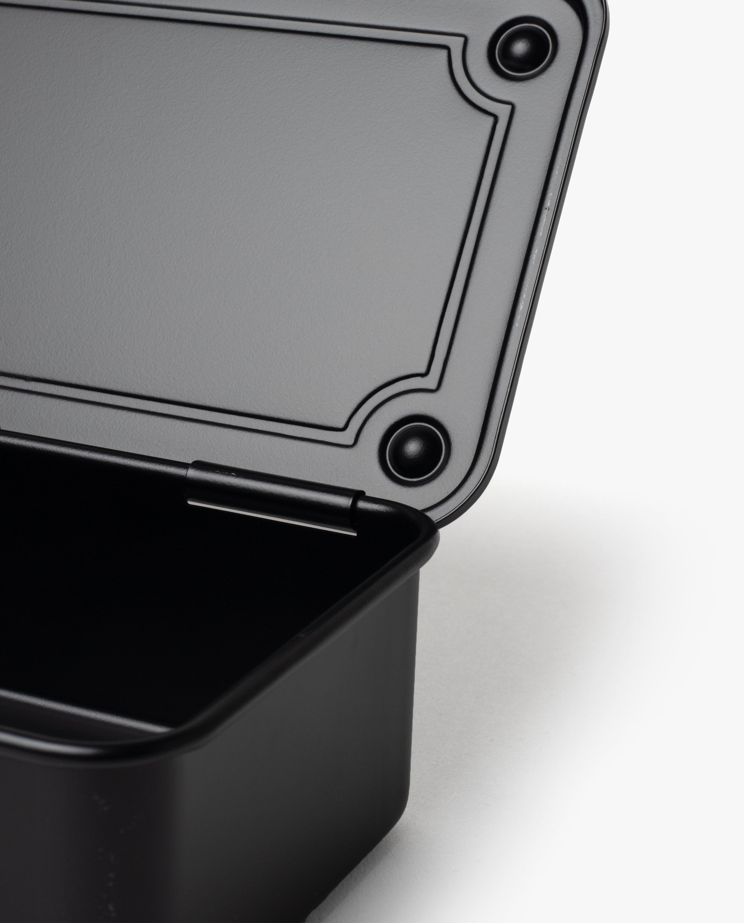 A close-up of an open Toyo Steel Stackable Storage Box T-190 (Black) with its lid partially raised, revealing the interior and textured lid edge against a white background, highlighting its functional design.