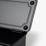 A close-up of an open Toyo Steel Stackable Storage Box T-190 (Black) with its lid partially raised, revealing the interior and textured lid edge against a white background, highlighting its functional design.