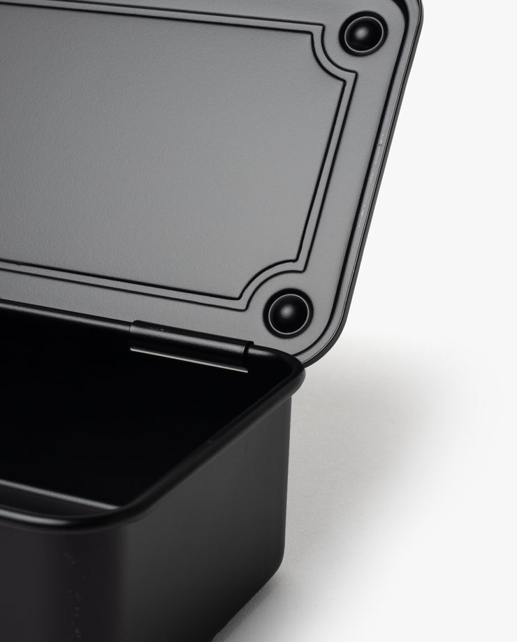 A close-up of an open Toyo Steel Stackable Storage Box T-190 (Black) with its lid partially raised, revealing the interior and textured lid edge against a white background, highlighting its functional design.