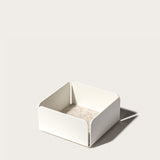 The Gather Small Tray (1x1 - White) features a minimalist white square design with open sides, rounded corners, and a beige interior. Made in Pennsylvania, it’s ideal as a desk organizer and casts a right-side shadow on light surfaces.