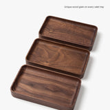Three handcrafted Valet Tray (Walnut - Small) pieces, made in Pennsylvania with unique wood grain patterns, are displayed in a staggered arrangement on a white background. Caption: Unique wood grain on every valet tray.