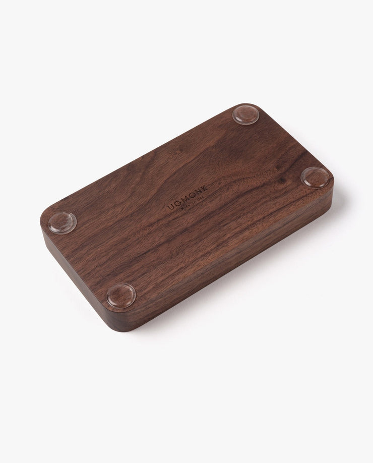 The Valet Tray (Walnut - Small) is a handcrafted rectangular tray made in Pennsylvania, featuring rounded edges, four clear rubber feet at each corner, and UGMONK engraved in the center—ideal for organizing your everyday essentials.