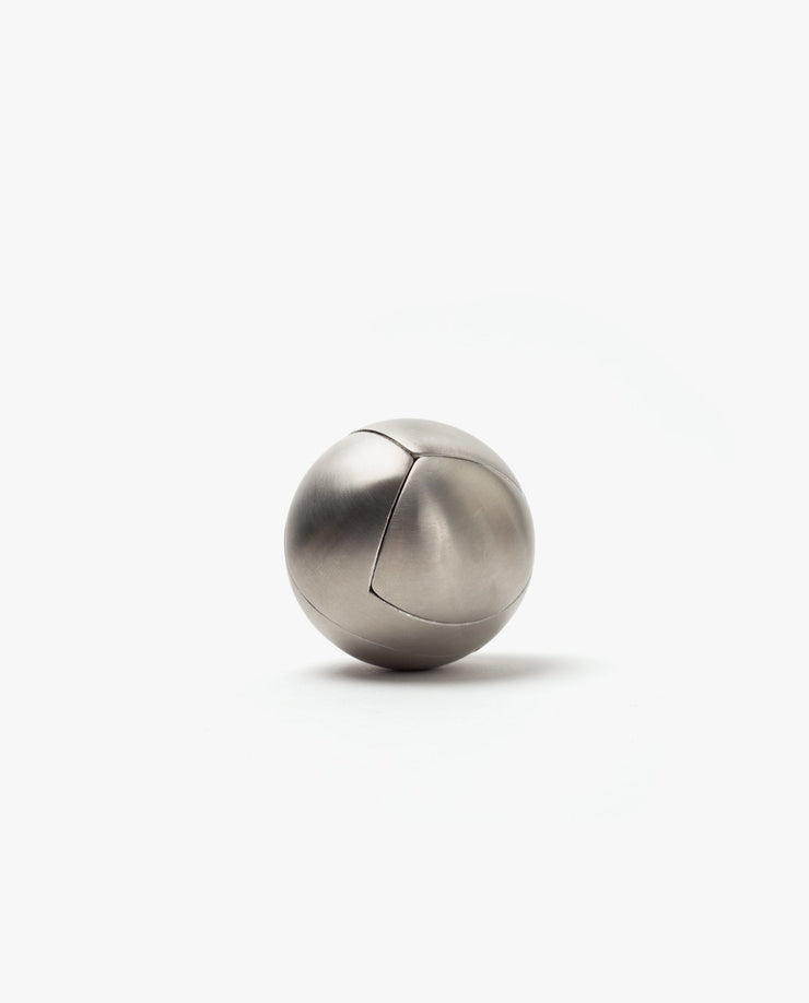 The Craighill Venn Puzzle (Stainless Steel) is a smooth, metallic sphere with a subtle curved seam, elegantly resting on a plain white background.