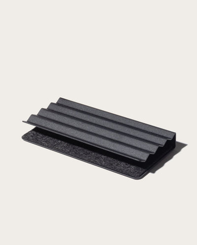 The Gather Zigzag Tray (2x1 - Black) is a black, rectangular tray with ridged, layered design, made from powder-coated steel, shown on a light neutral background and ideal as a modern desk organizer.