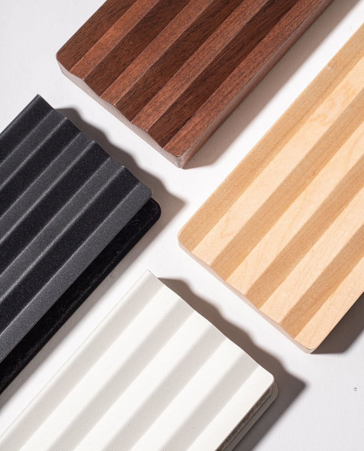 Four rectangular, ribbed panels appear diagonally on a white surface, echoing the style of the Gather Zigzag Tray (2x1 - Black); each tray is a different color and placed at a corner of the image.